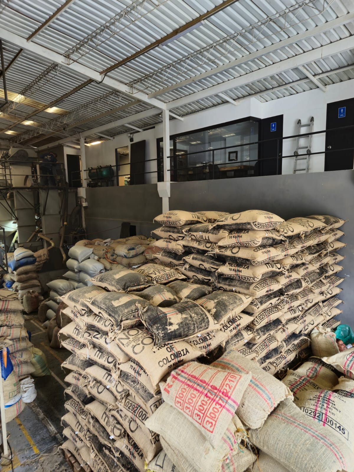 Stacked jute bags of Colombian green coffee in the Invercafé warehouse