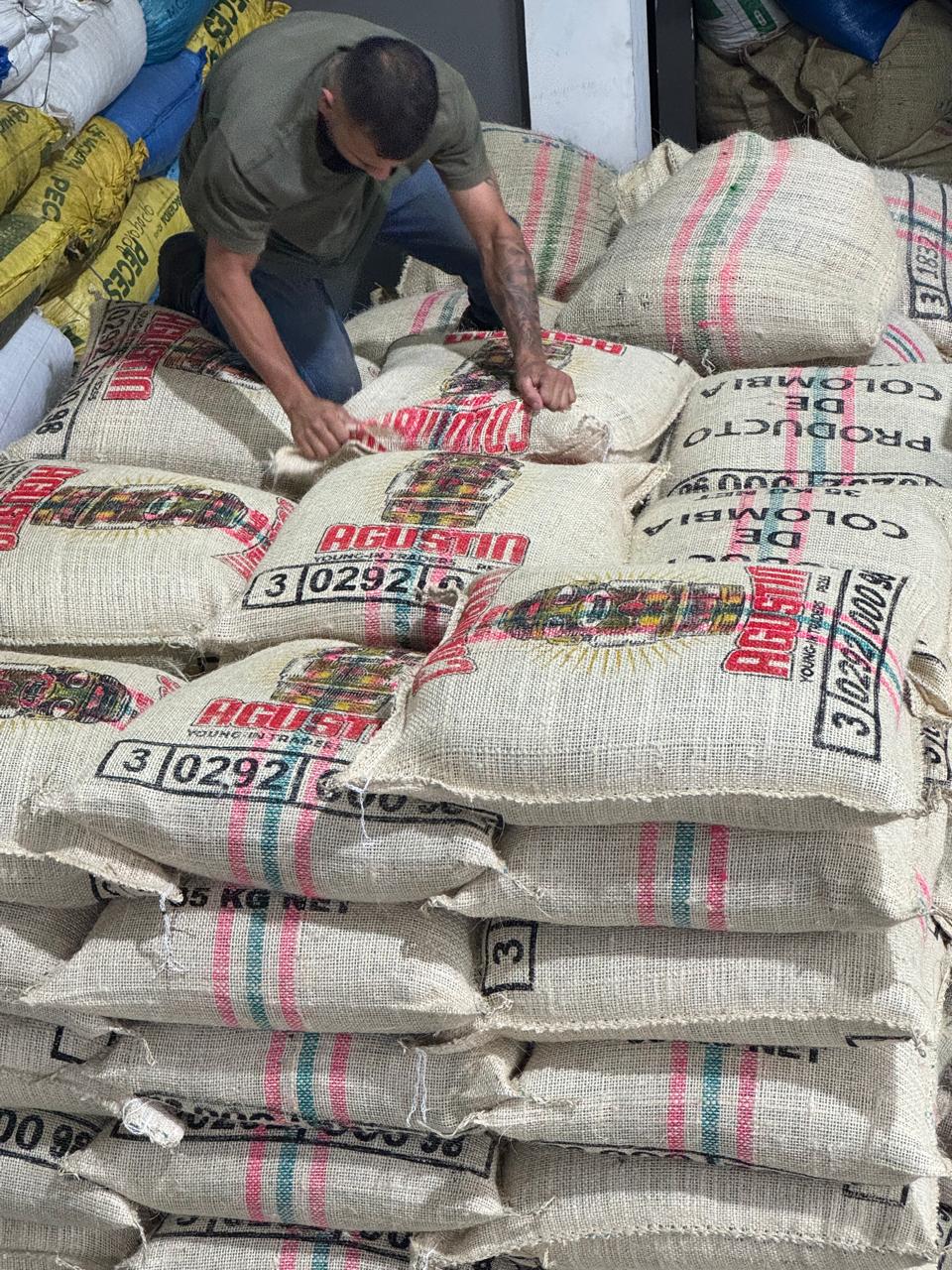 Worker stacking jute bags of Colombian green coffee for export